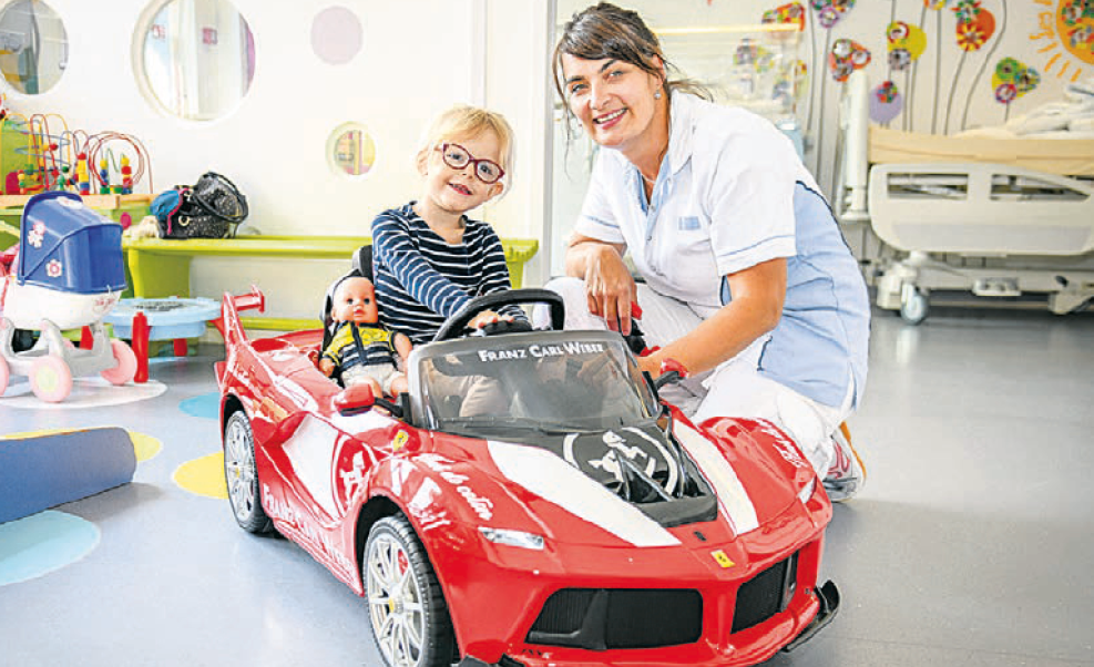 Cassandra au volant de la Ferrari avec son chauffeur Coralie Gros, infirmière en pédiatrie.